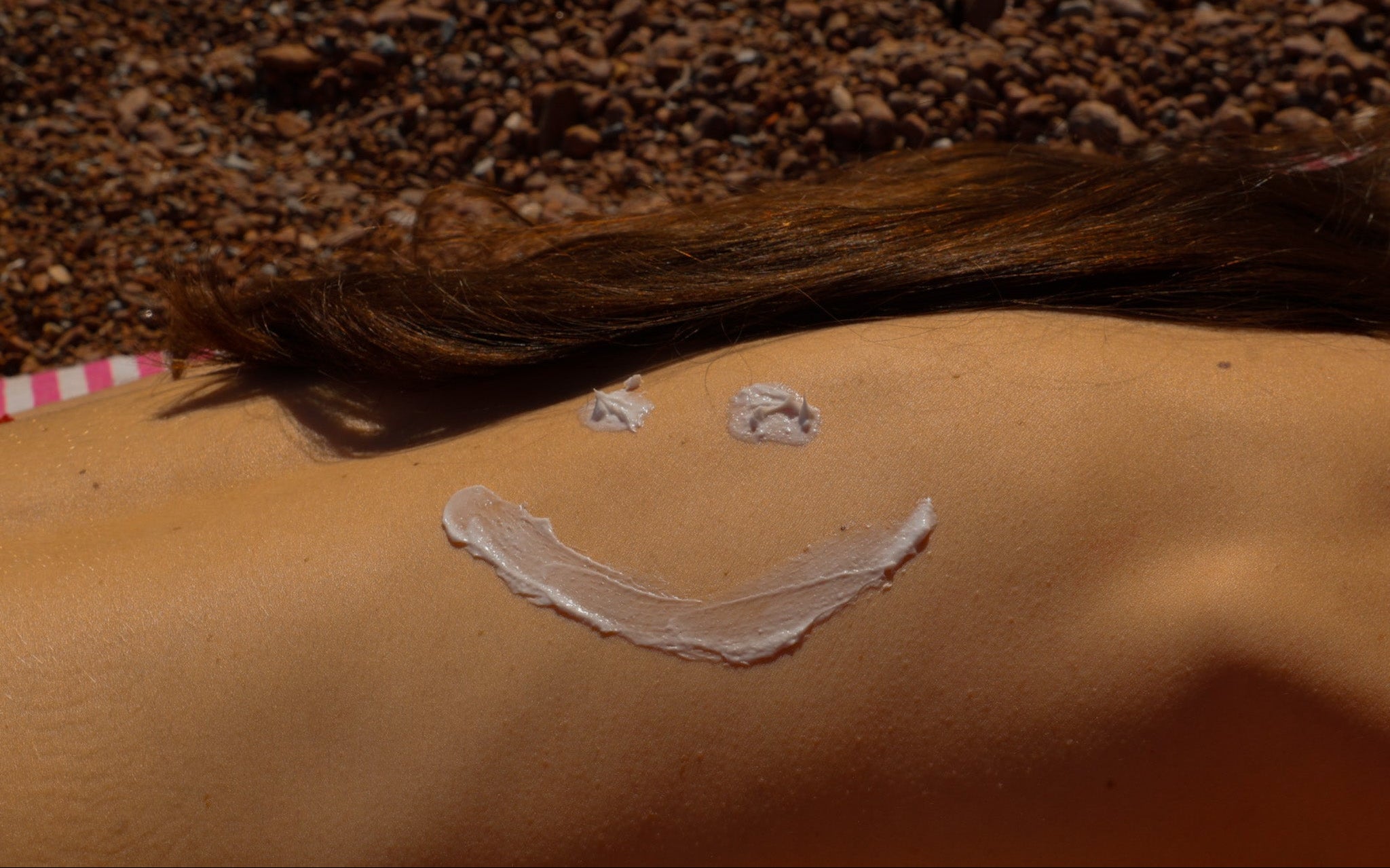 Femme de dos avec dessin smiley crème sur la peau ambiance lifestyle plage Manaiki
