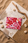 Pochette de plage TIARE imprimé feuille framboise. Conçue dans la matière de nos maillots de bain, idéale pour transporter pads, maillot et essentiels d'été.